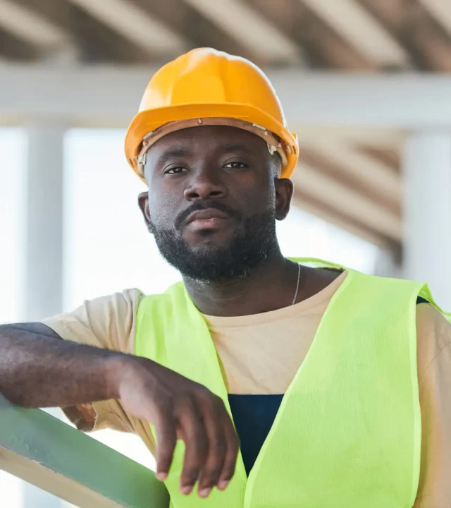 Portrait of smiling construction worker wearing hardhat while posing against concrete wall, copy space